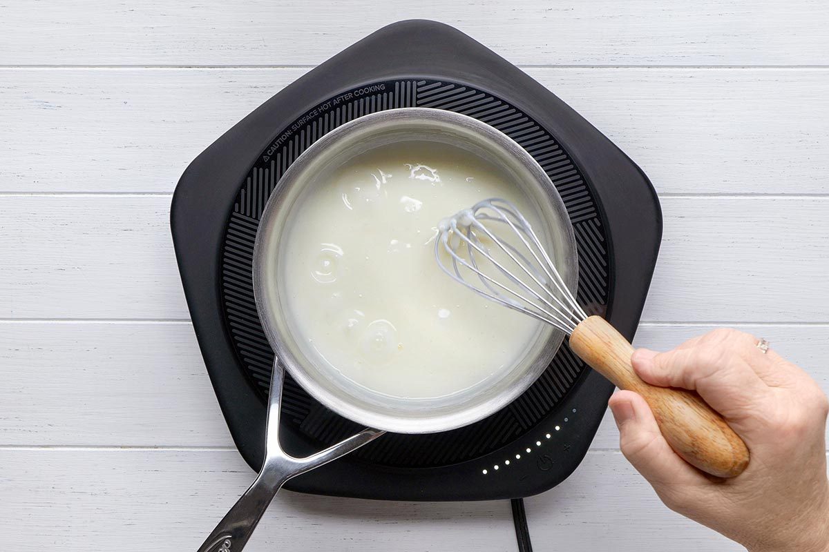 Sugar, cornstarch and milk being whisked in a small heavy saucepan