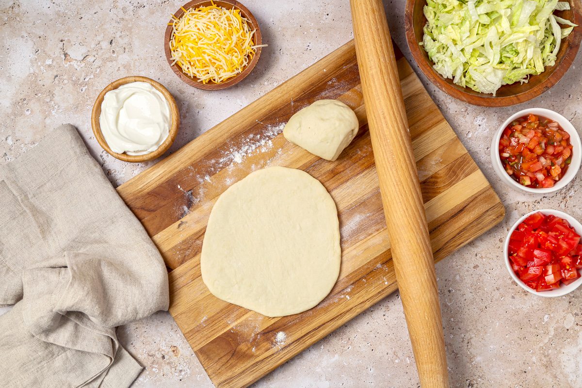 Rolling dough into a 4-inch circle on a floured surface.