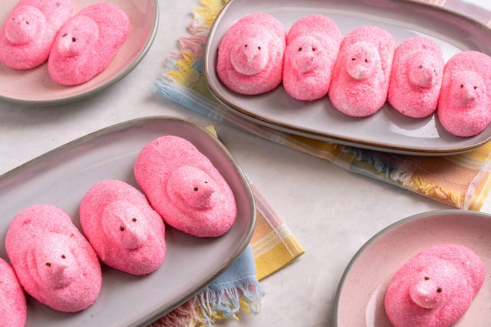 Four plates of pink marshmallow chicks arranged in rows on a light table, with colorful napkins underneath.