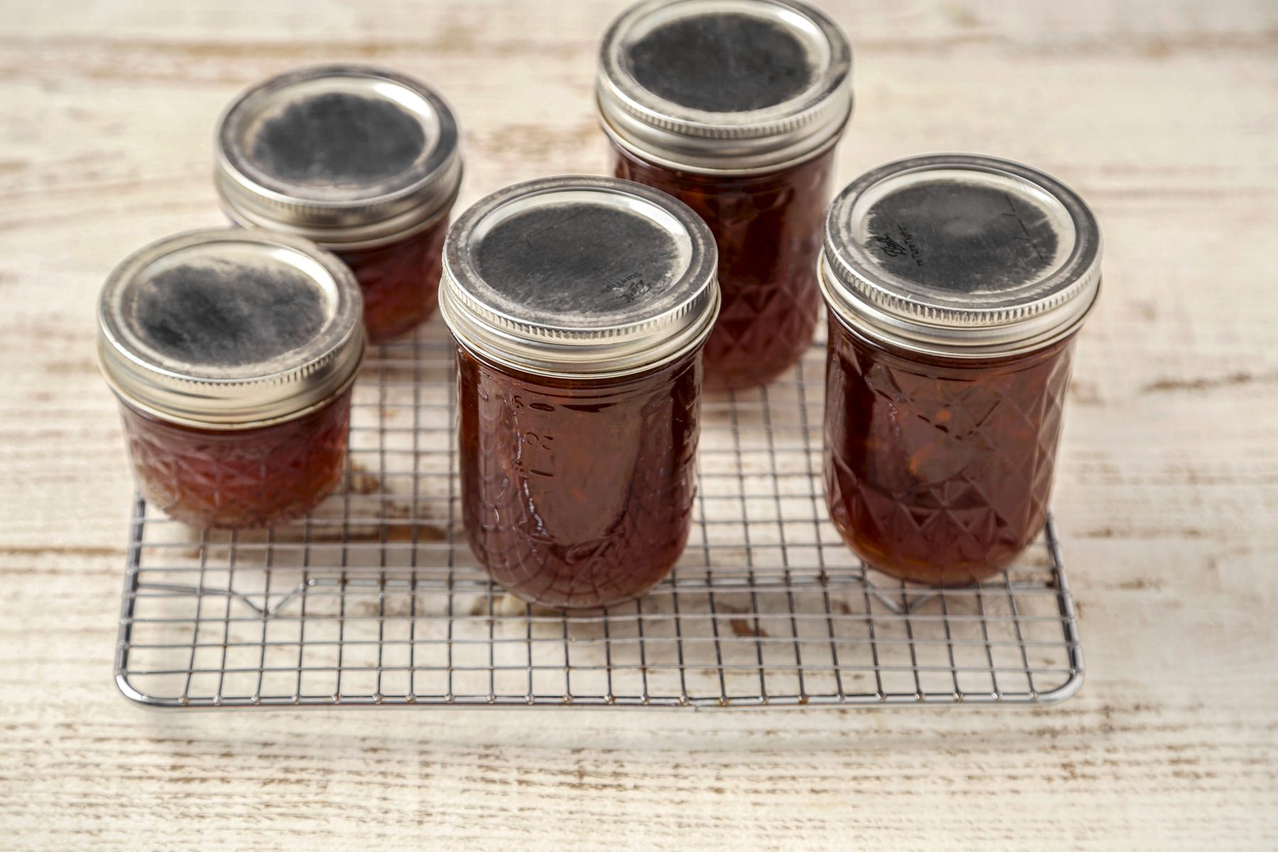 Jars processed and filled with onion jam cooling on a wire rack