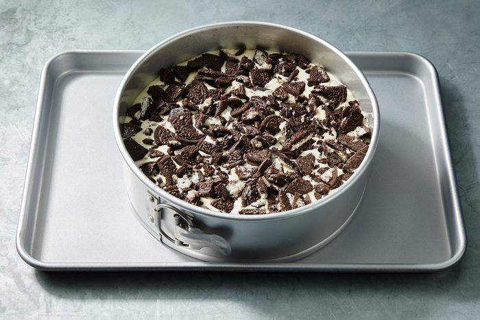 High angle shot of placed pan on a baking sheet; Bake at 325 degree until center is almost set 60-65 minutes; Cool on a wire rack for 10 minutes; Carefully run a knife around the edge of pan to loosen; cool 1 hour longer; Refrigerate overnight; Remove side of pan; grey surface;