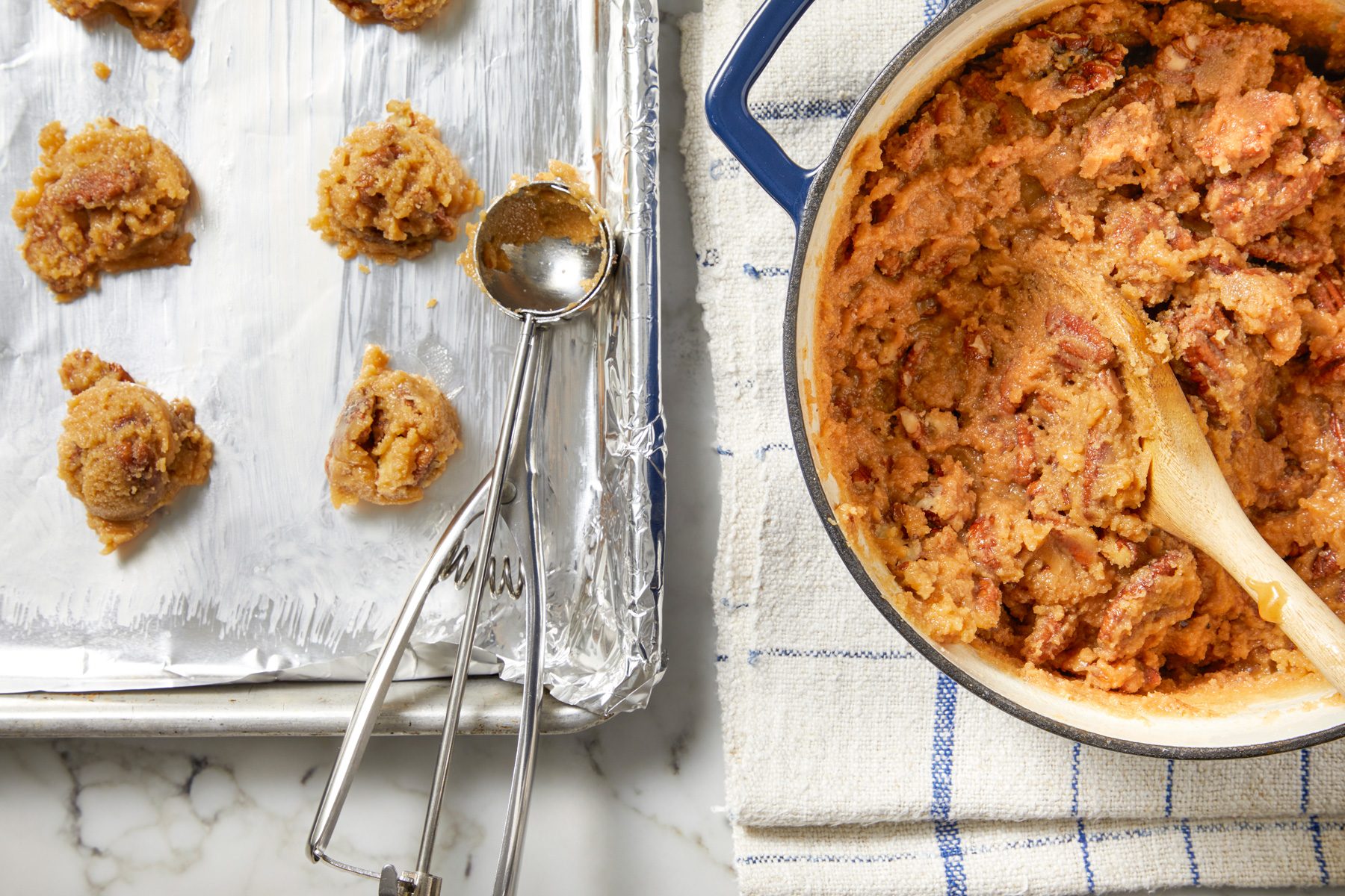 Overhead shot of Quickly drop by rounded tablespoonfuls onto prepared baking sheets; Let stand until pralines are set and no longer glossy; Refrigerate until completely set about 1 hour; Store in an airtight container in the refrigerator; napkin; marble surface;