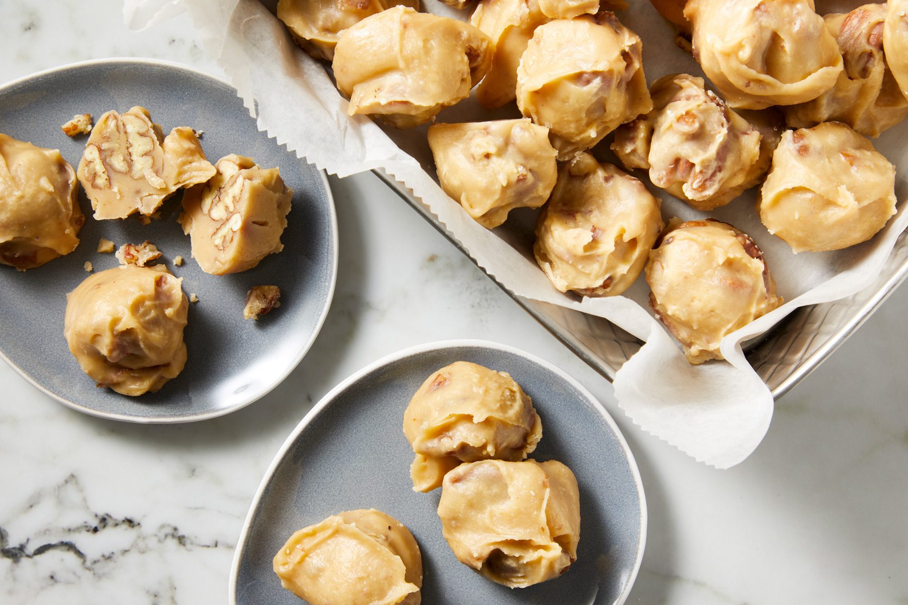 Overhead shot of Texas Pecan Pralines; in a large tray; served on two plates; marble surface;