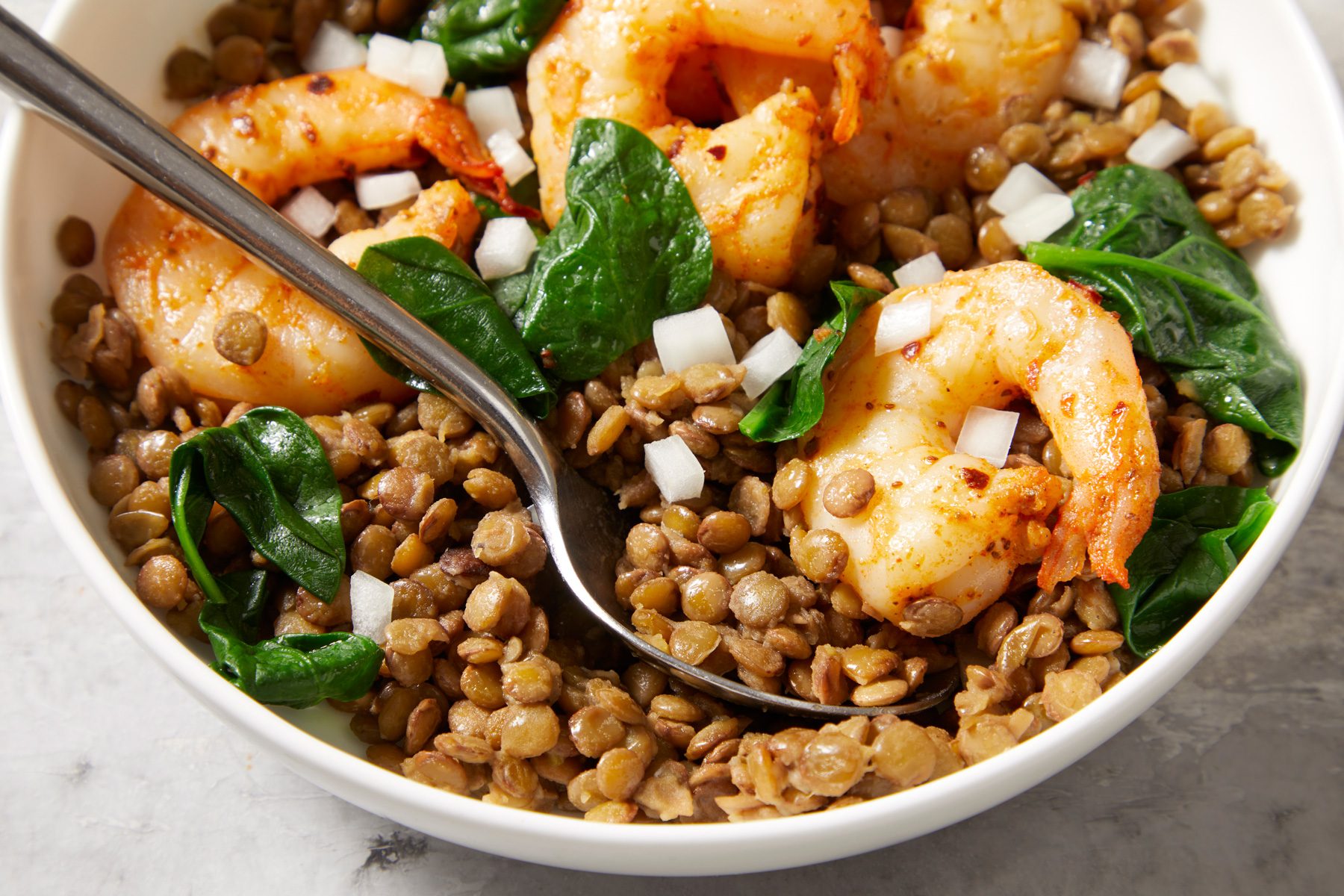closeup shot of East Coast Shrimp and Lentil Bowl, a spoon is placed into the mixture