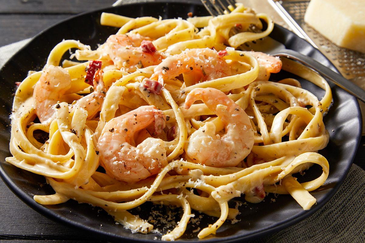 Close shot of Spicy Shrimp Fettuccine Alfredo; Garnished with grated parmesan cheese