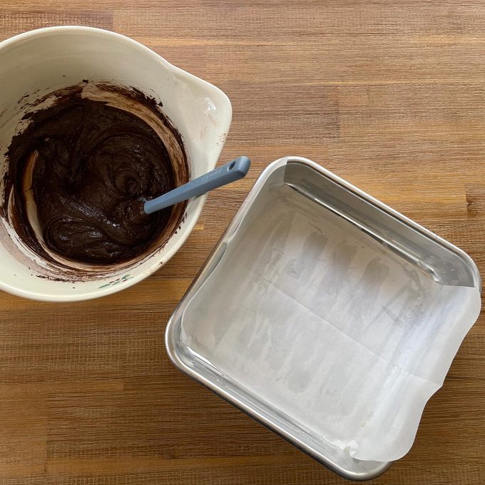 Bowl of brownie batter and a greased aluminum brownie sheet to the right