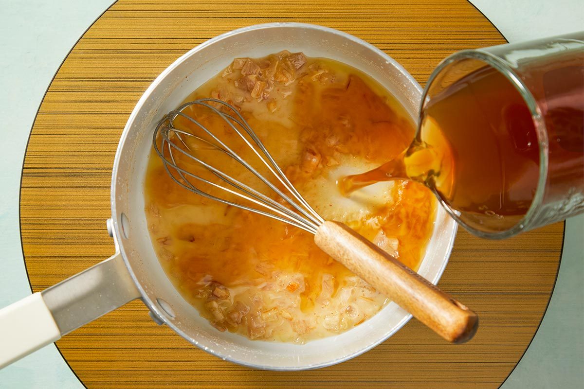 Beef broth being poured in a sauce pan
