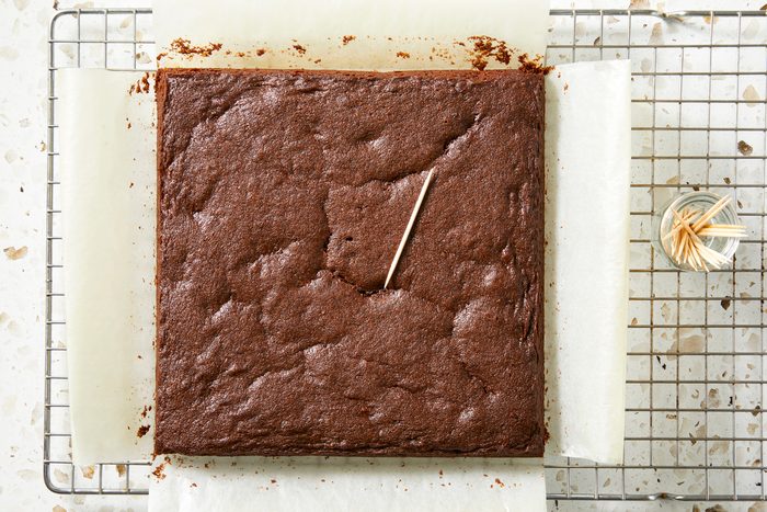 Overhead shot; Use edges of the parchment paper to lift brownies from the pan; Allow brownies to cool on a wire rack at least one hour before cutting; marble surface;