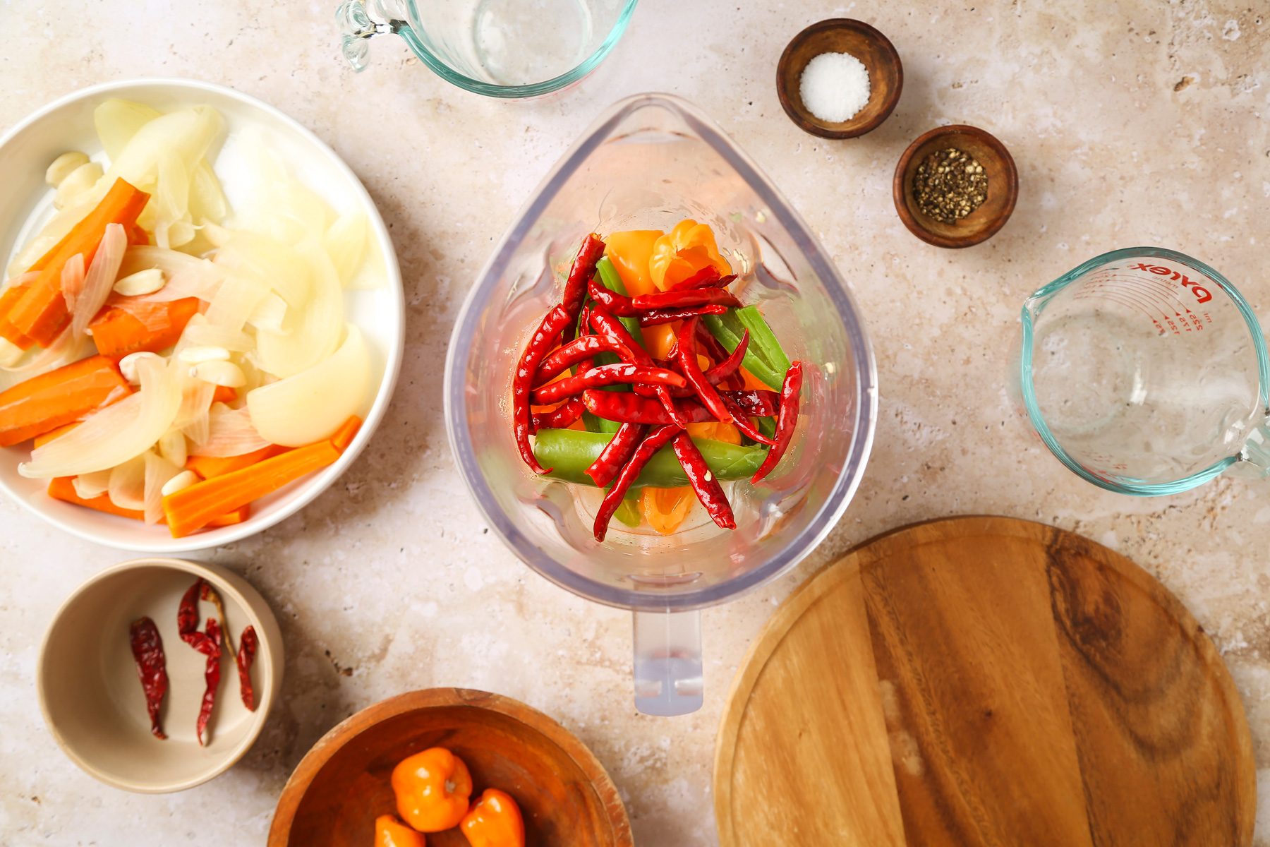 Overhead shot; In a well-ventilated area; fill a 6-qt. stockpot three-quarters with water; bring to a boil; add carrots; onion and garlic; Return to a boil; cook until soft 20-22 minutes; Remove with a slotted spoon to a bowl; add peppers to stockpot; return to a boil; Boil 1 minute; drain; Place water; vinegar; lime juice; salt and pepper in a blender; add vegetables; cover and process until smooth; Return to stockpot; bring to a boil; round wooden board; marble surface;