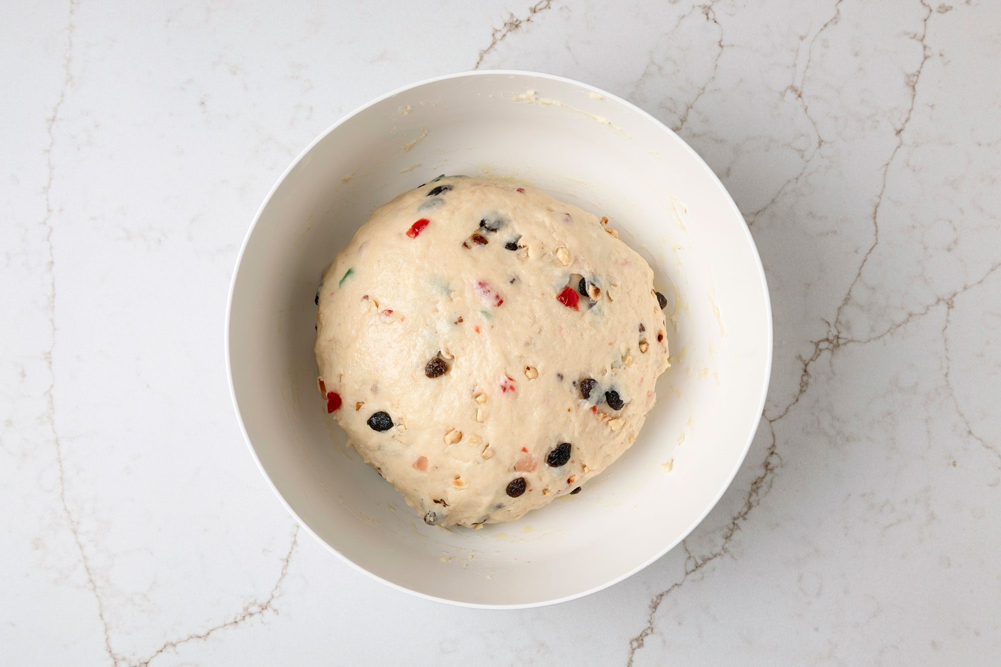 overhead shot of a bowl filled with a light colored dough the bowl is placed on a light marbled surface underneath