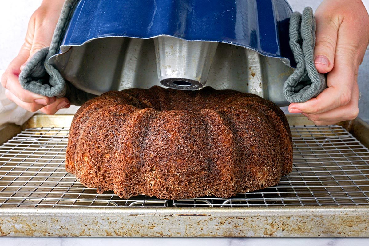 Unmolding a bundt cake from a well-greased blue pan onto a wire rack
