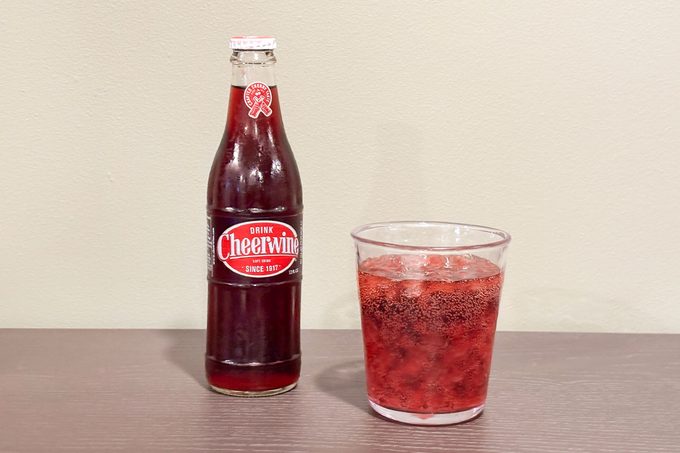 A glass filled with Cheerwine drink placed with cheerwine bottle
