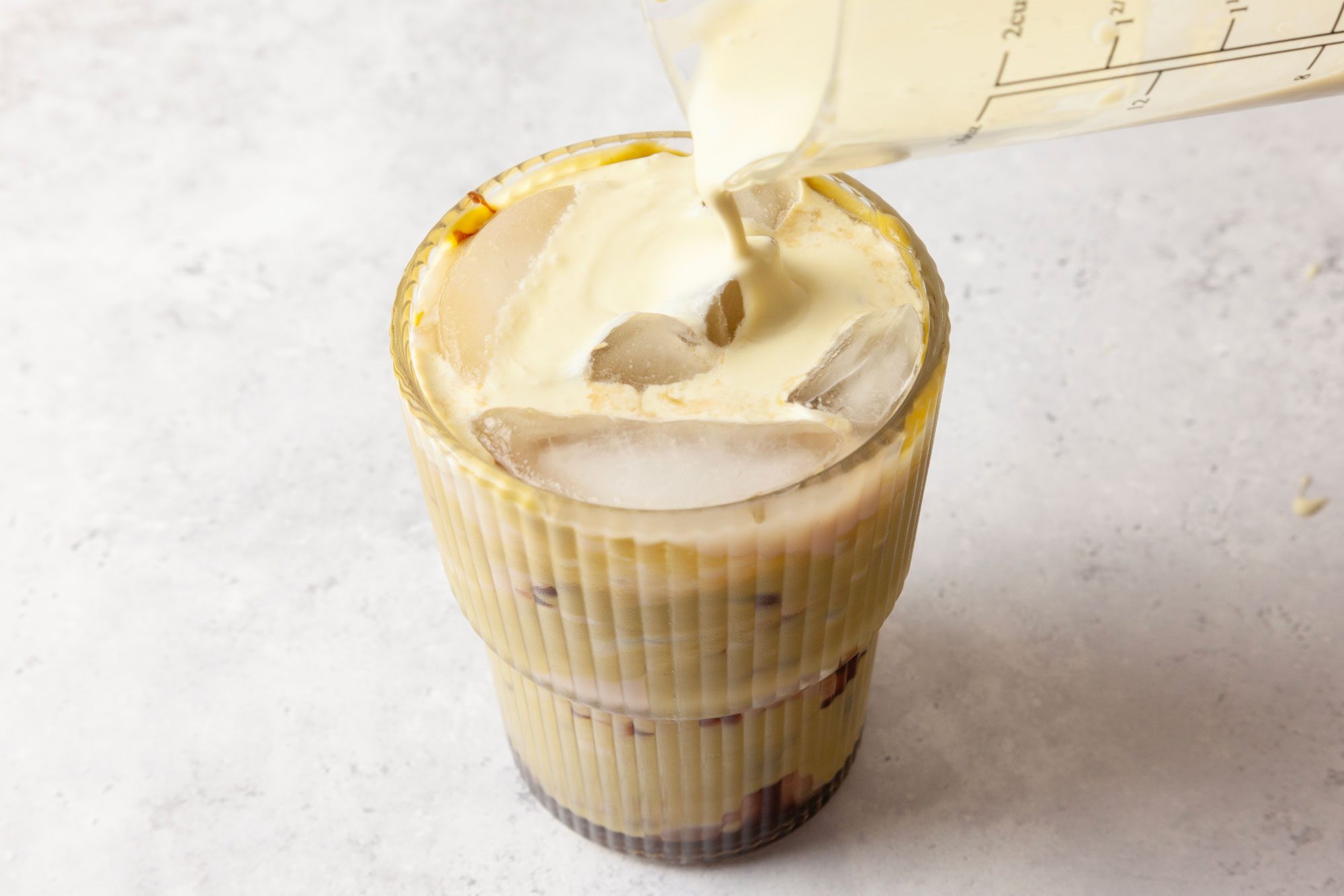 Gently pour the pistachio cold foam over the latte