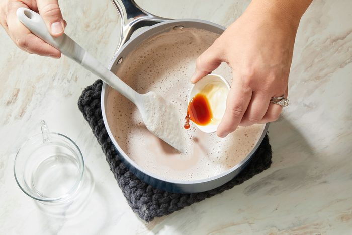 Overhead shot of remove saucepan from the heat; stir in vanilla; Ladle into mugs; spatula; marble surface