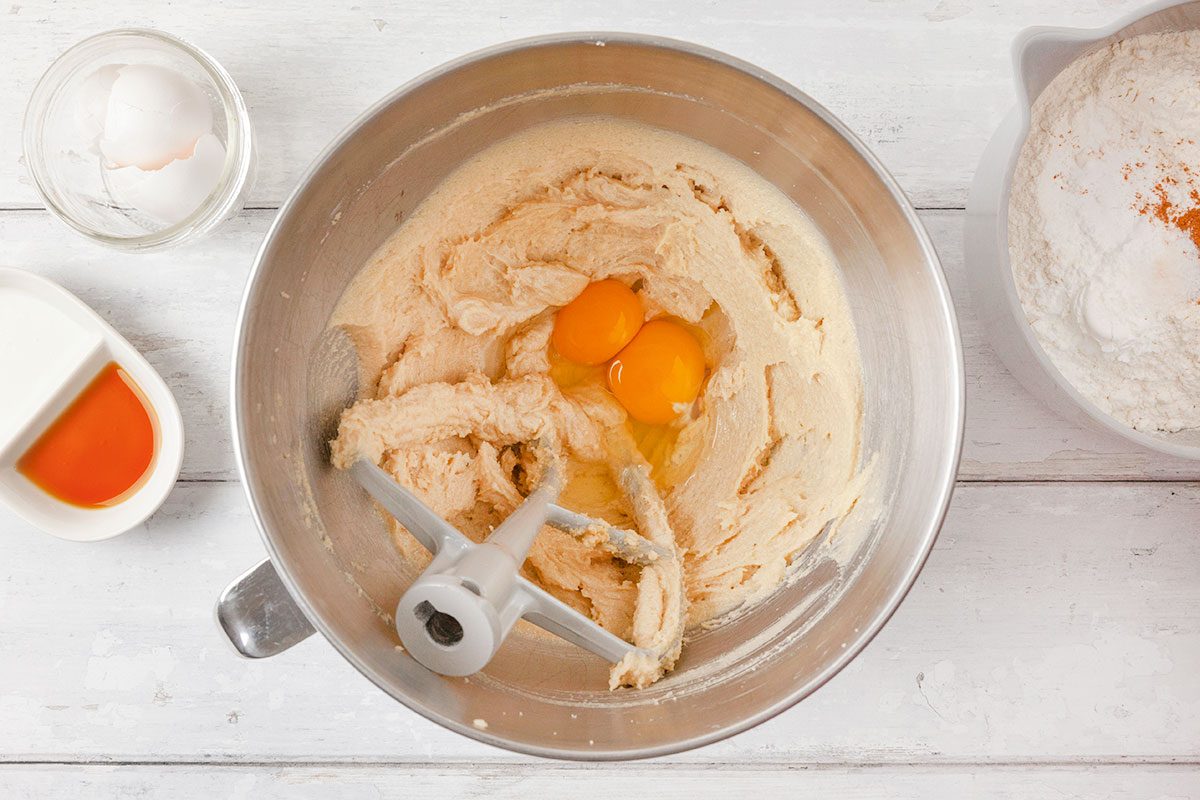whole egg with yolks being mixed in cream the butter, granulated sugar and brown sugar mixture