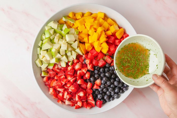 lime juice, honey and mint mixture juice being pured in a fruit nowl