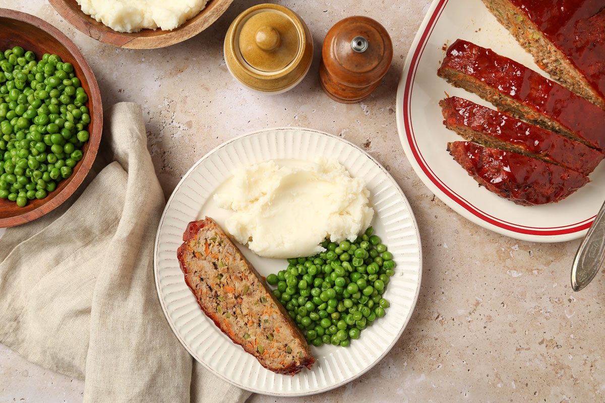 Bison Meat Loaf served on a plate with peas and mashed potatoes