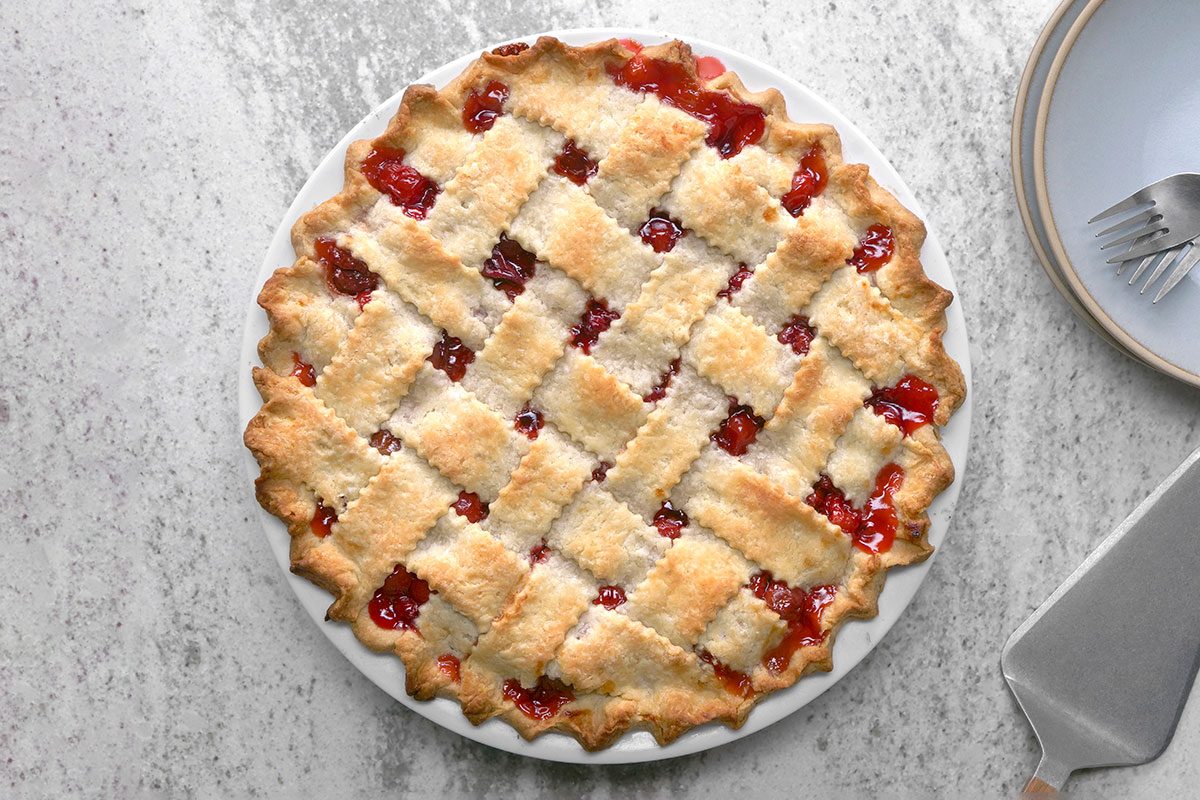 Lattice Pie Crust with a golden brown lattice crust sits in a white pie dish on a gray countertop