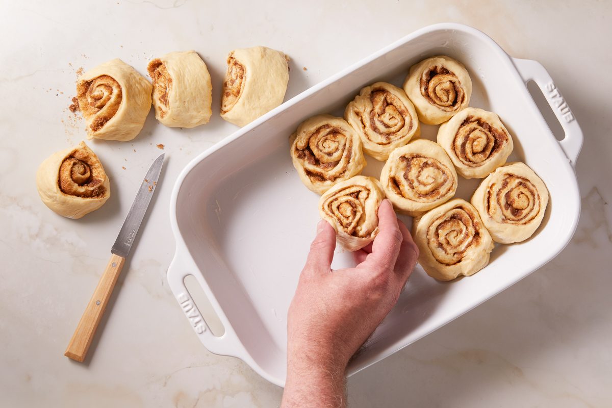 Placing the rolls, cut side down, in a greased 13x9-inch baking pan