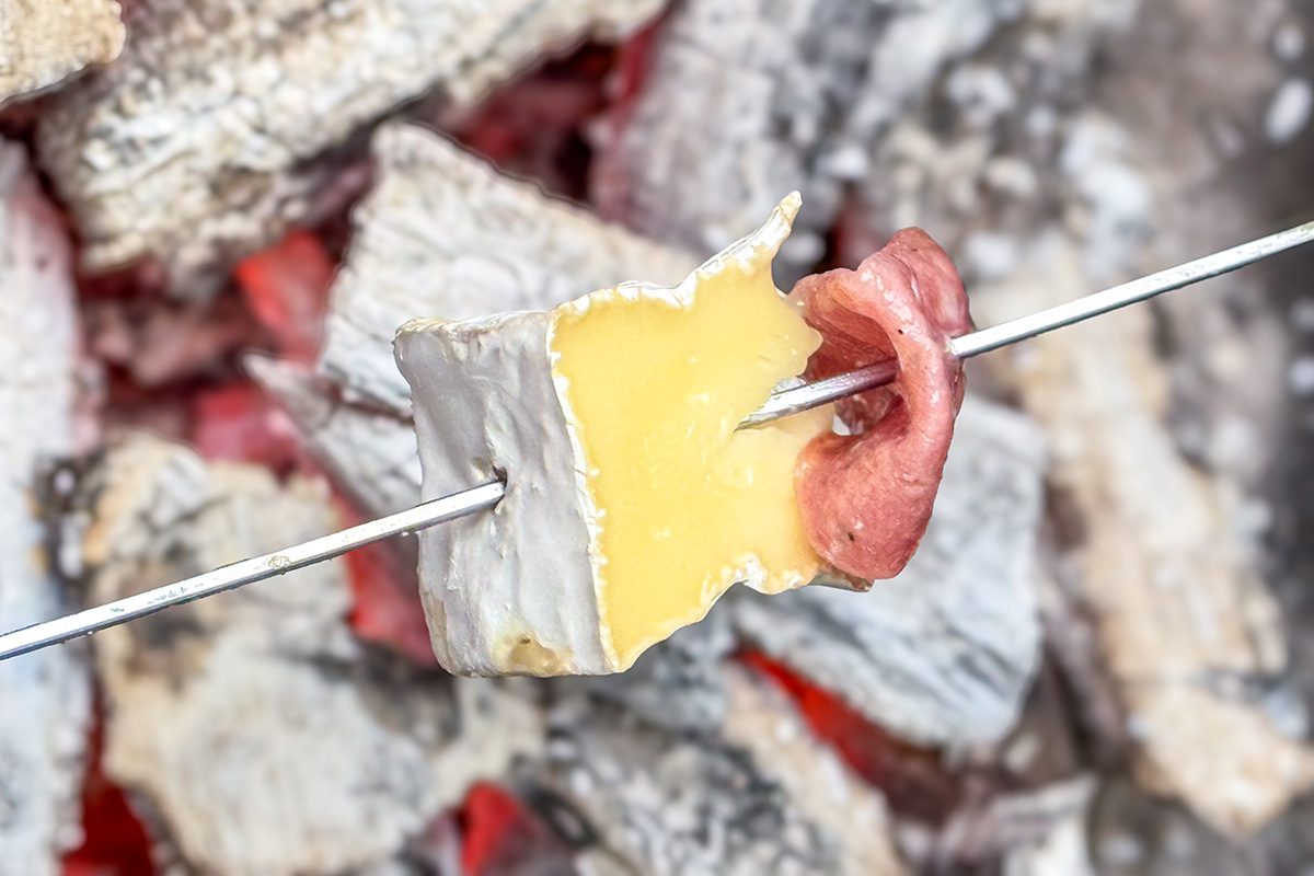 Cheese and Meat on a stick heated above a charcoal grill