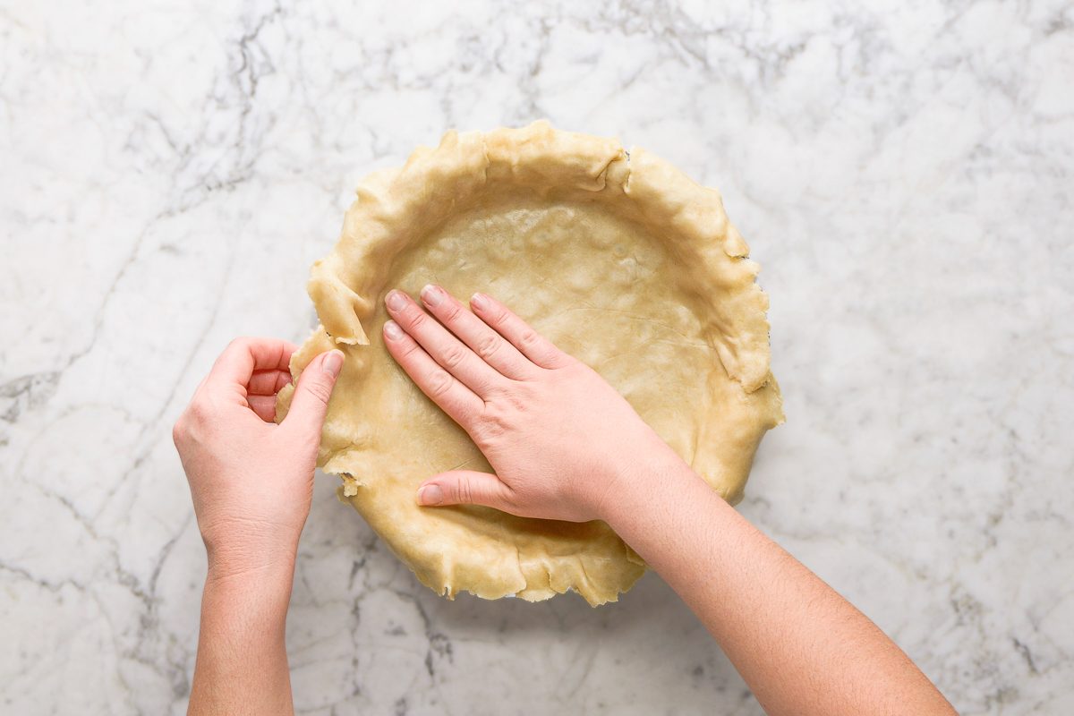 Placing the pastry over the layer of pecans in the bottom of the pie plate