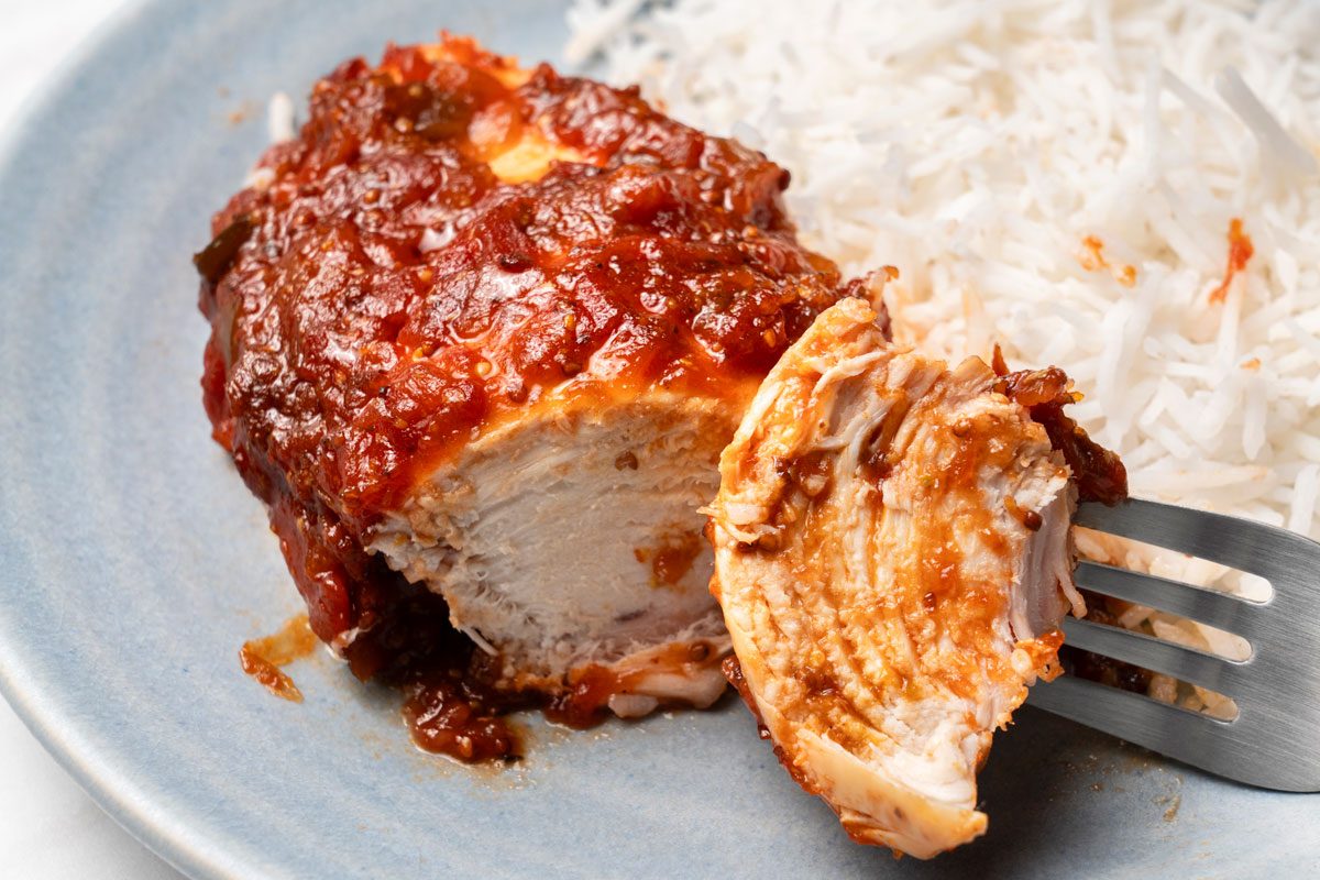 Closeup shot of Chicken Picante served with rice on two light blue ceramic plates; all set on a marble surface;