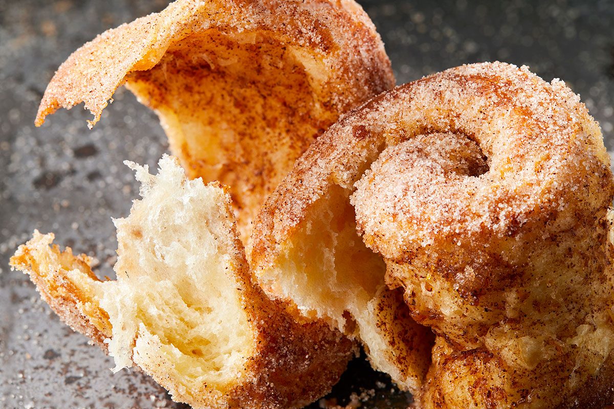 Close-up shot of a Morning Buns torn open to reveal its soft; airy interior and golden; flaky layers dusted with cinnamon sugar.