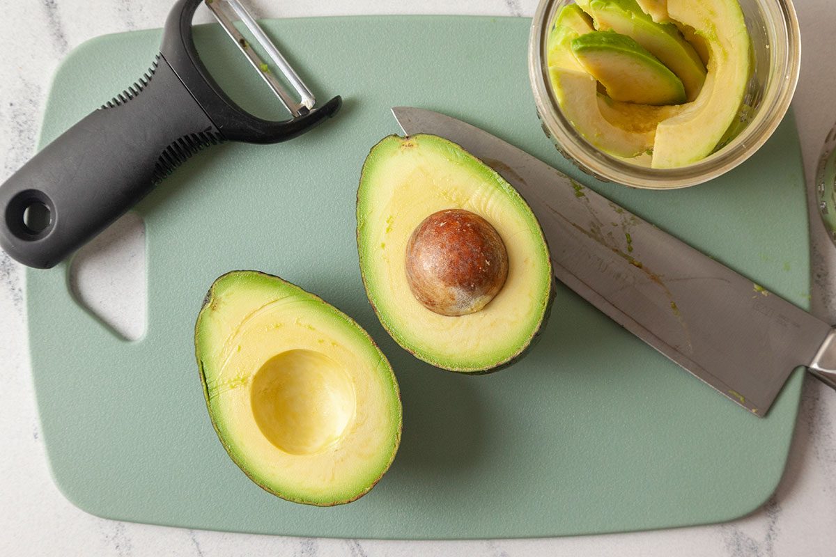 Avocado peeled and cut into half on a cutting board