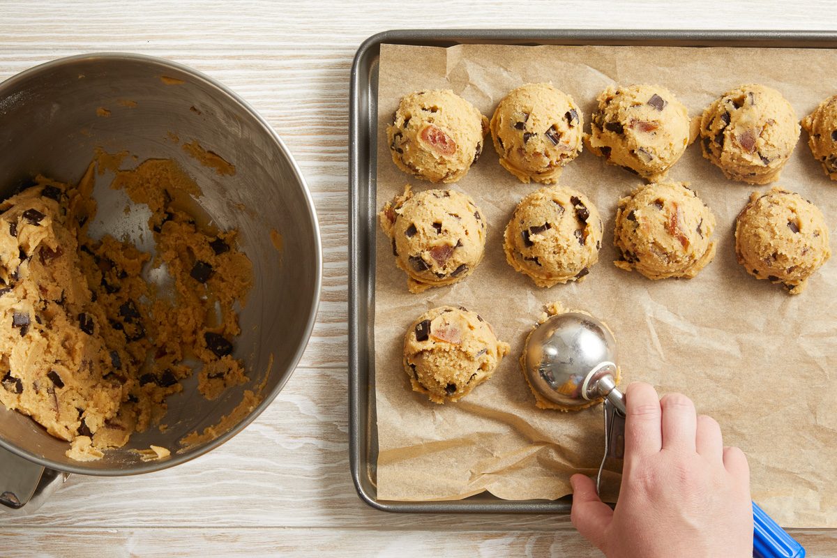 cookie dough balls being placed 2 inches apart onto parchment-lined baking sheets