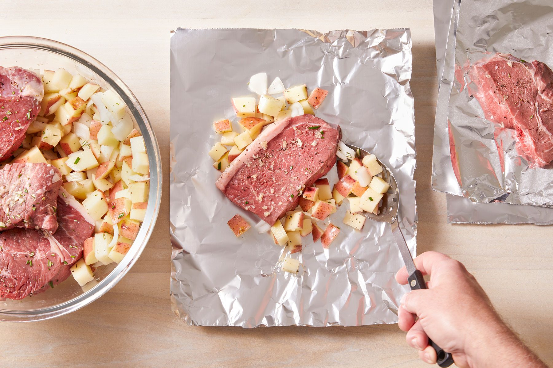 Dividing the steak and potato mixture among eight 18x12-inch pieces of heavy-duty foil.