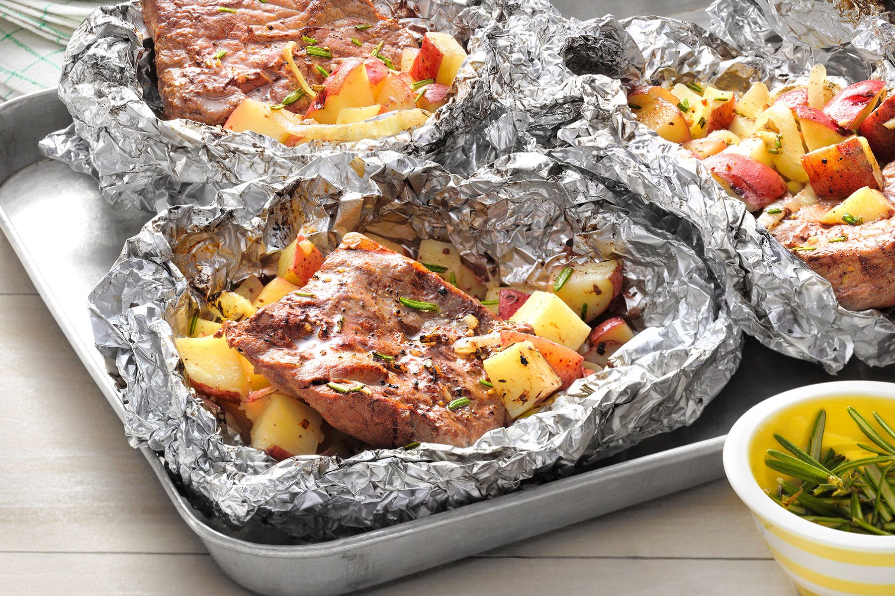 Steak And Potato Foil Packs opened and placed in a tray with garnishing bowl on side.