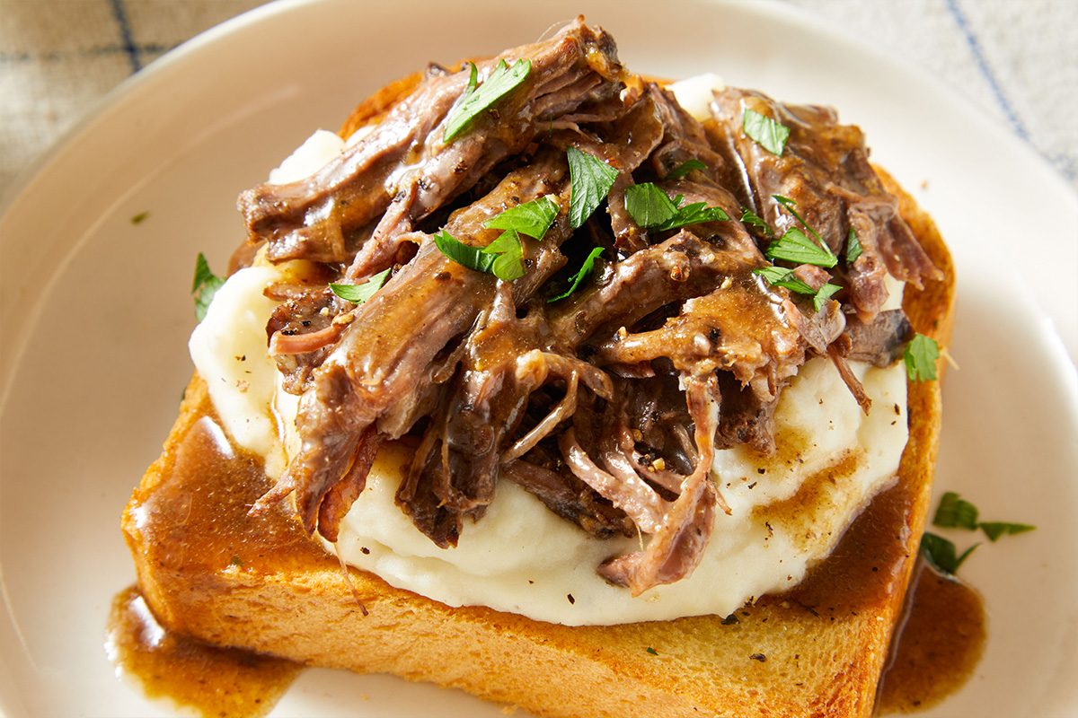 Close-up shot of Beef Manhattan drizzled with brown gravy and sprinkled with parsley.