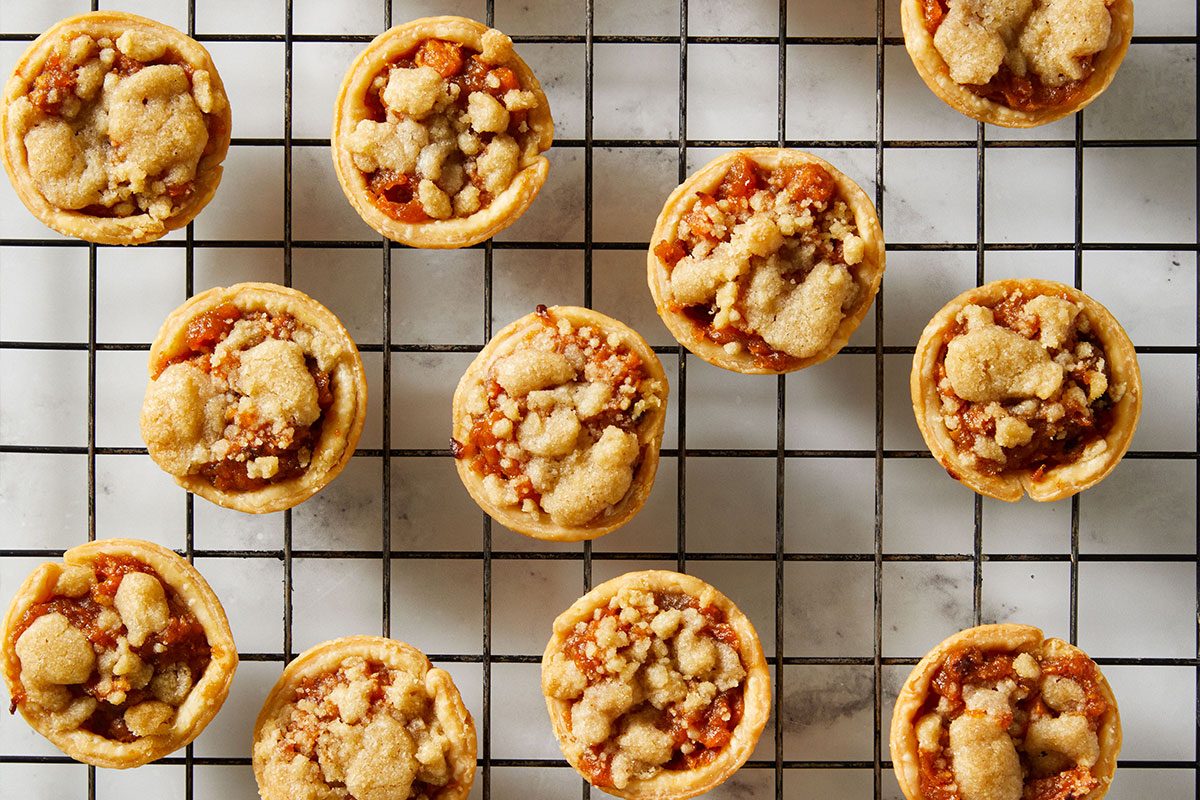 Overhead shot of baked Mini Sweet Potato Pies cooling on a wire rack, arranged in neat rows.