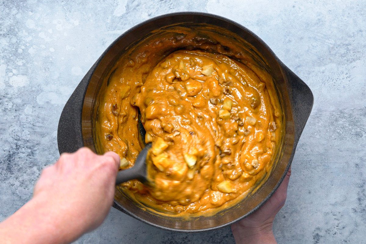 chopped apples and walnuts being folded in with batter