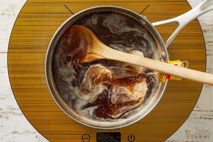 tea bags, sugar, ginger, cinnamon stick and water in a saucepan