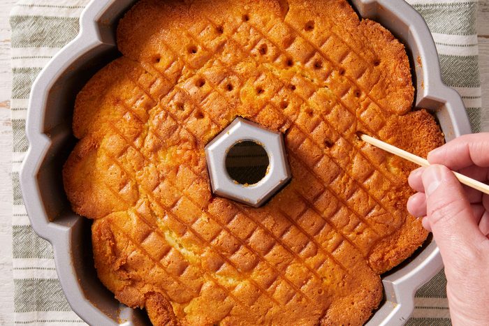 Using a small skewer, poking holes in the coconut rum cake.