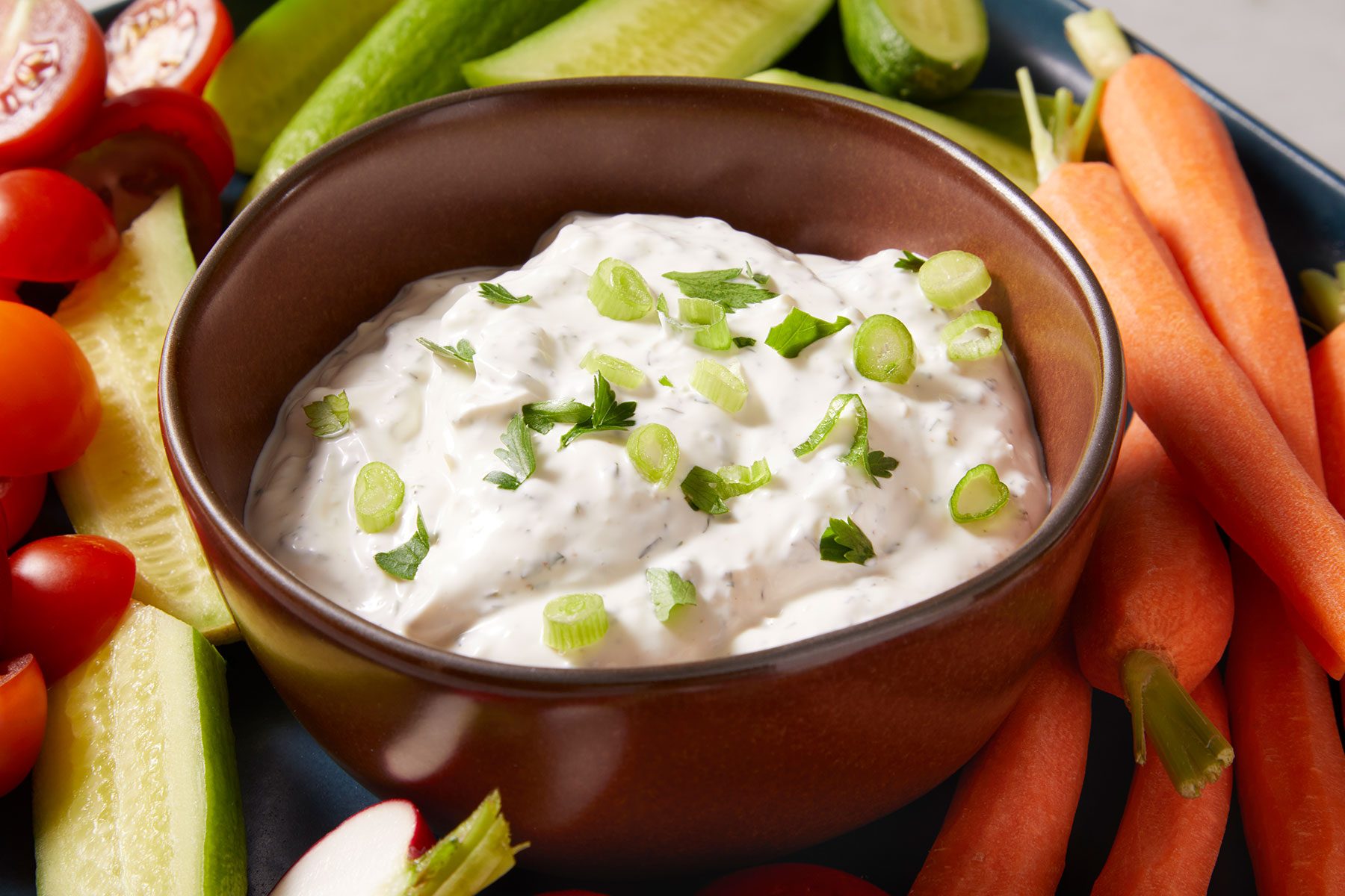 Crudite Dip in a bowl with a lot of raw vegetables around it.