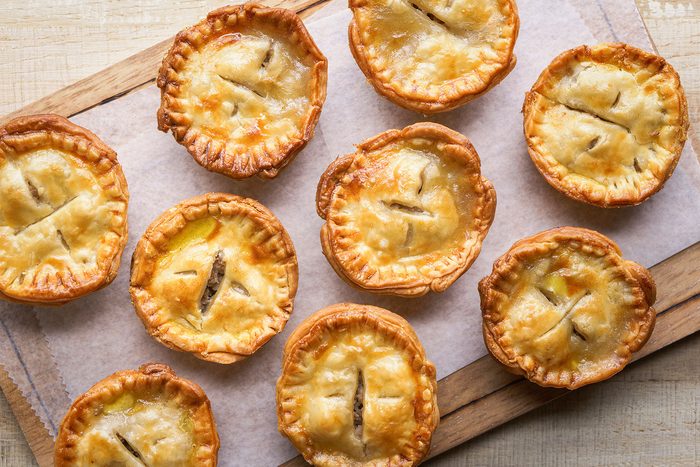 Mini Pork Pies baked and kept on a wooden board with lining sheet.