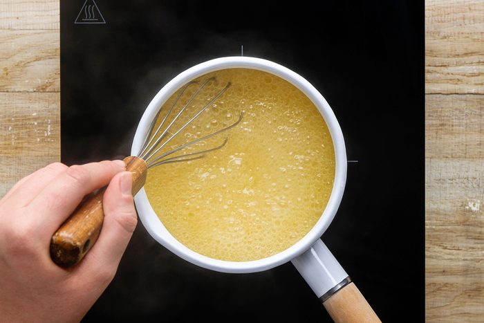 Whisking together the cornstarch and chicken broth until they're blended in a small saucepan.