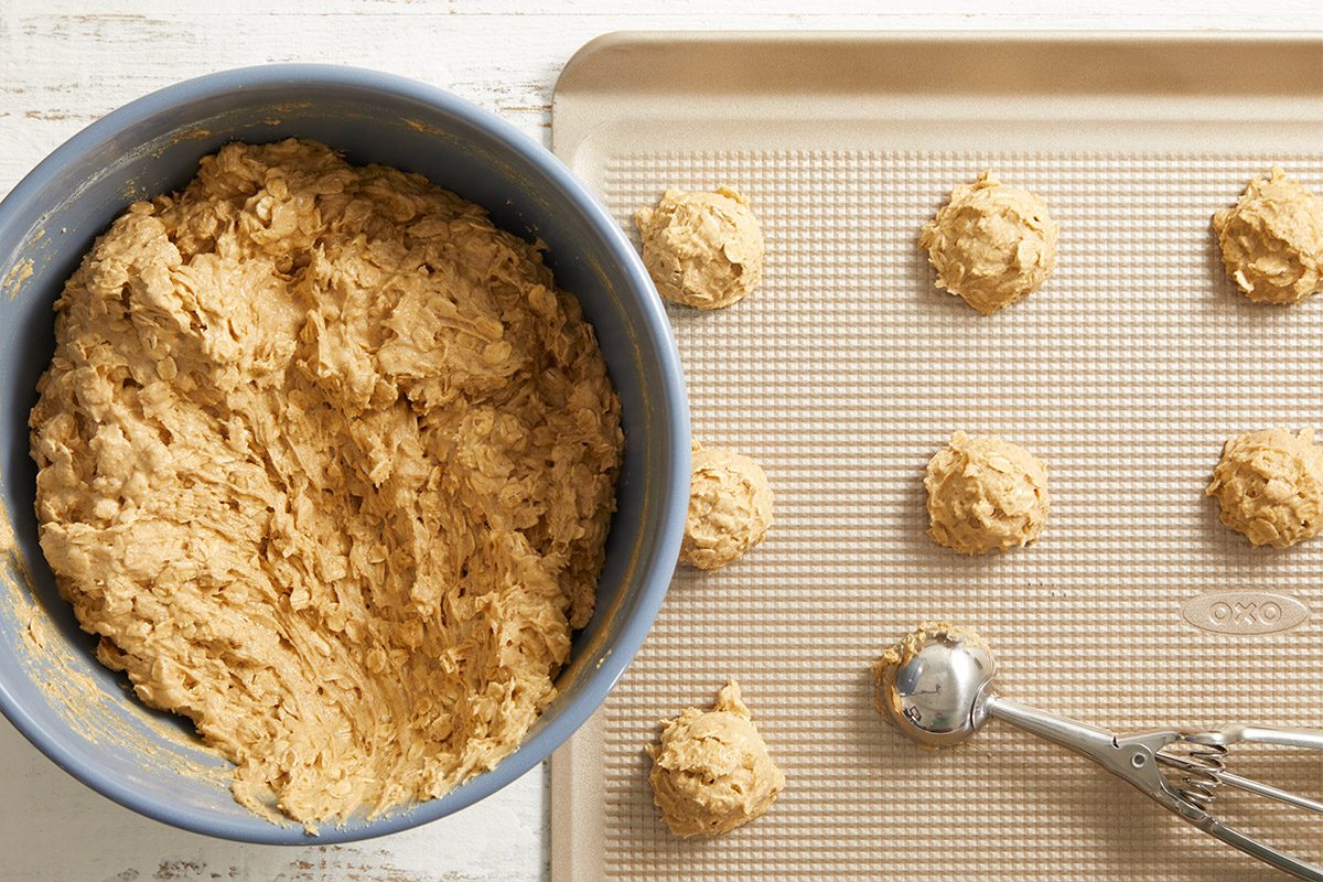 Overhead shot of cookie dough scooped into small mounds on a baking sheet lined with parchment paper, ready to bake.