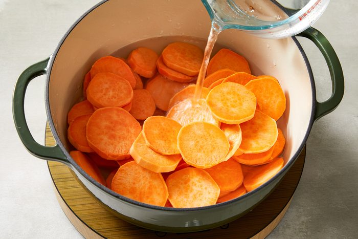 water being poured onto peeled sweet potatoes in a dutch oven