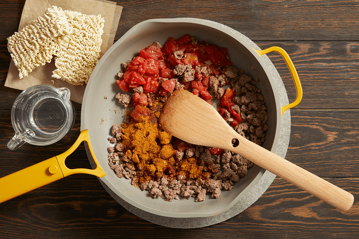 Cooking beef, onion, tomatoes and spices in a skillet