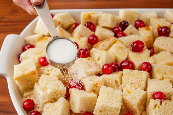 sprinkling sugar over bread and custard mixture layers