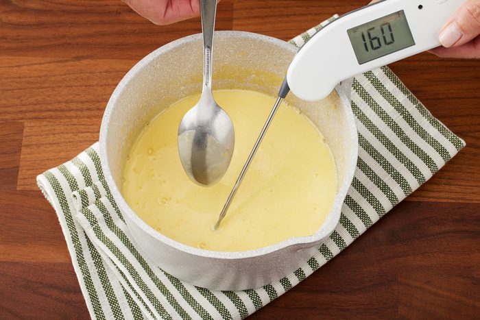 checking custard sauce temperature with a thermometer