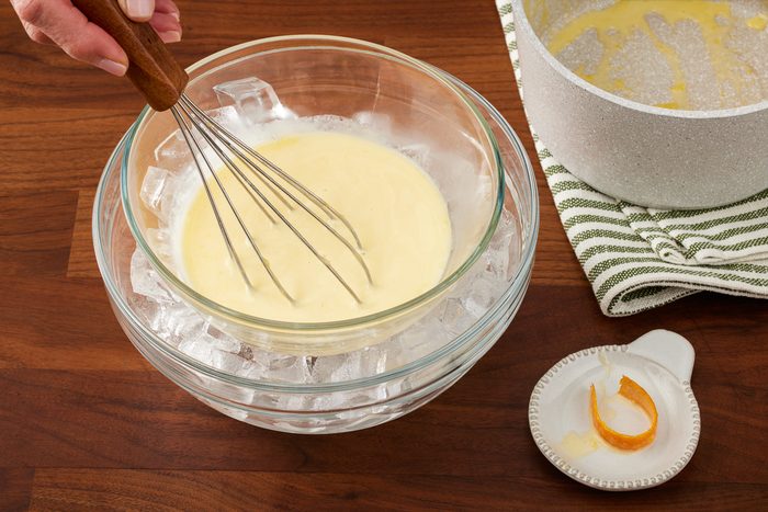 bowl with custard sauce in ice-water bath being stirred with a whisker