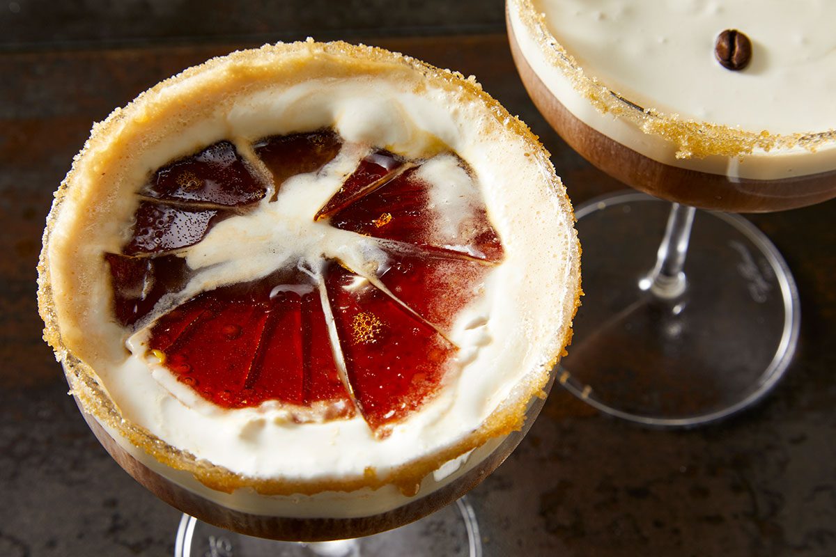 Closeup shot of a crème brûlée espresso martini with a cracked caramelized sugar topping, revealing the creamy layer beneath;