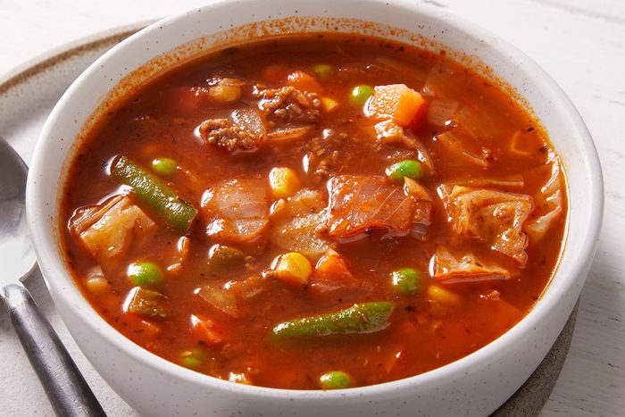 Close-up overhead shot of a white bowl filled with Italian Veggie Beef Soup showing beef pieces, green beans, and mixed vegetables in a tomato base.