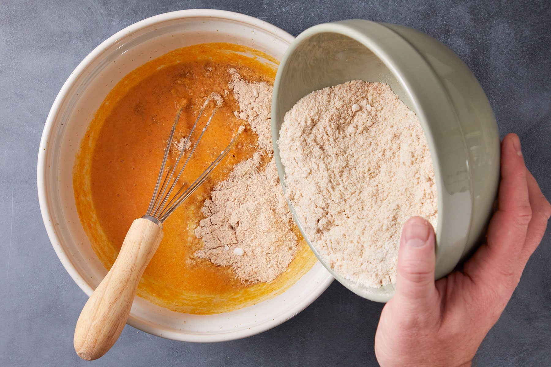 Adding dry ingredients to the wet ingredients of Keto Pumpkin Muffins before baking.