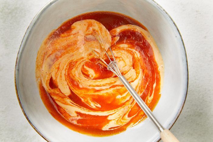 An overhead, horizontal step-by-step image of Thousand Island dressing mixed with Sriracha chili sauce in a bowl, creating a creamy, spicy sauce for Spicy Corned Beef Tacos.