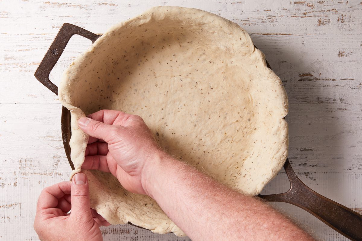 dough transferred to a skillet draping over edges